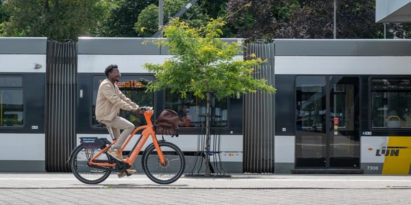 Fietser op een elektrische fiets met een tram op de achtergrond